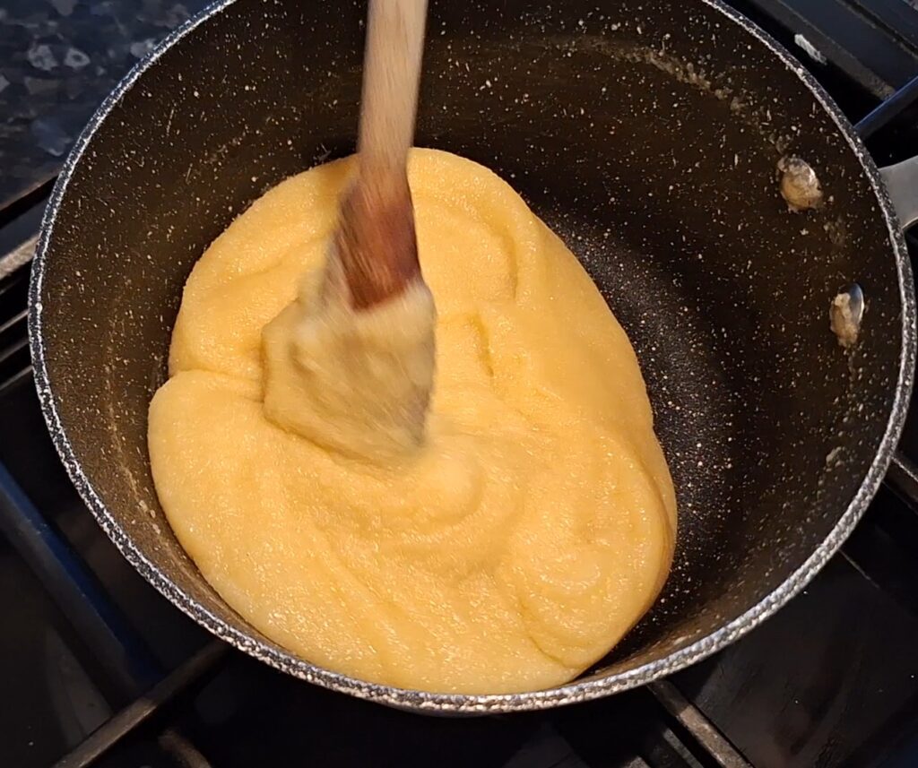 Mixture has come together into a mass and is sticking to the spoon.