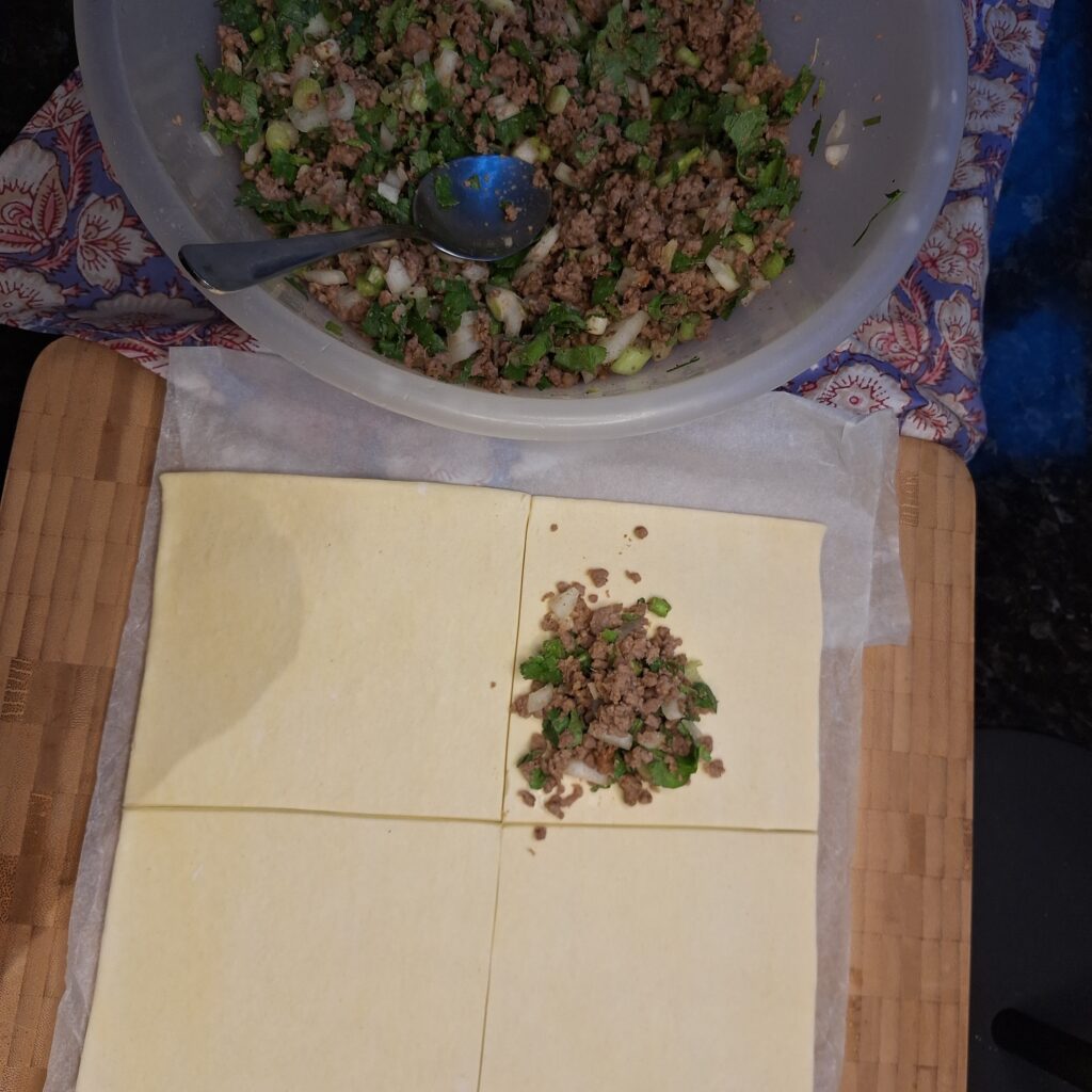 Keema applied to corner of puff pastry ready to fold