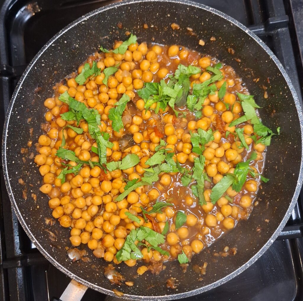 Freshly chopped coriander added to chickpea curry