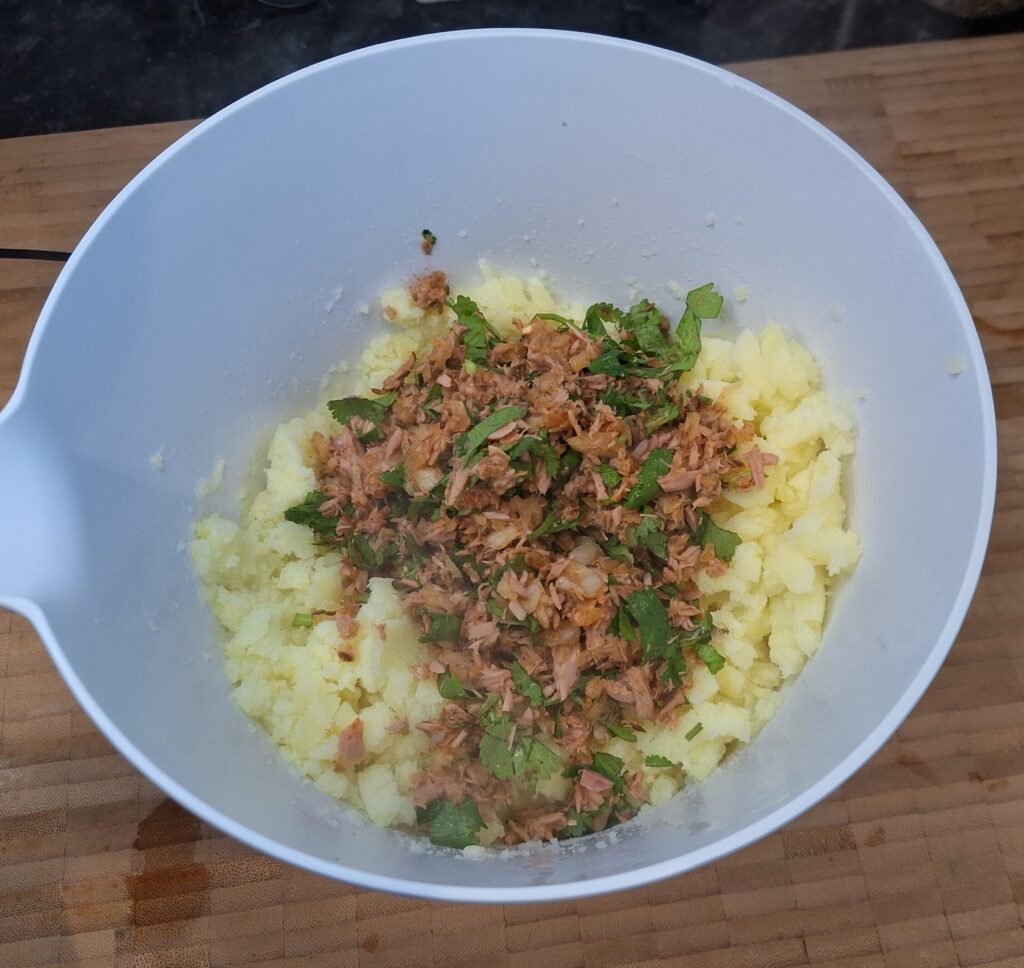 Tuna, potatoes and spices in the bowl ready to mix.