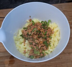 Tuna, potatoes and spices in the bowl ready to mix.