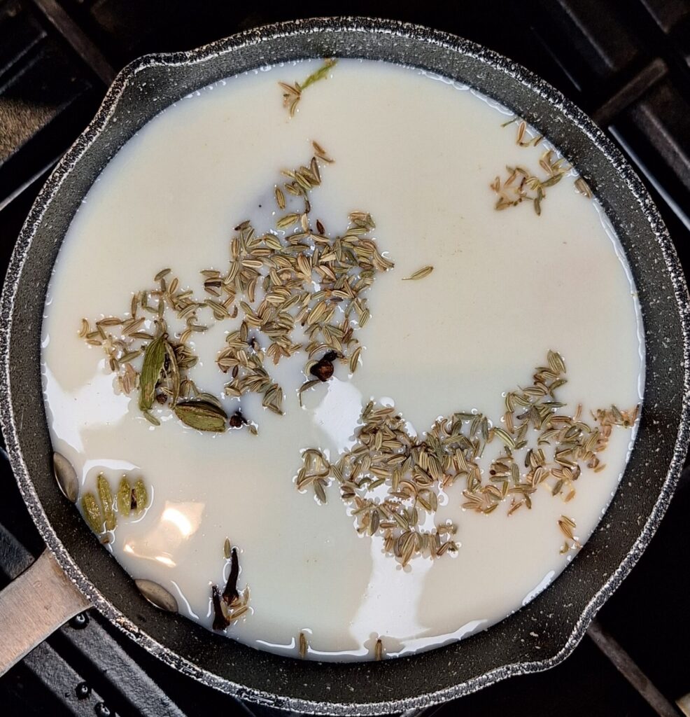 Milk, spices and tea bags in pan