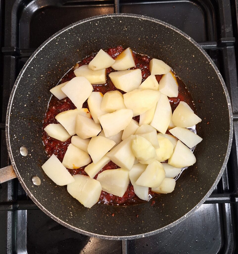 Add potatoes to tomato paste