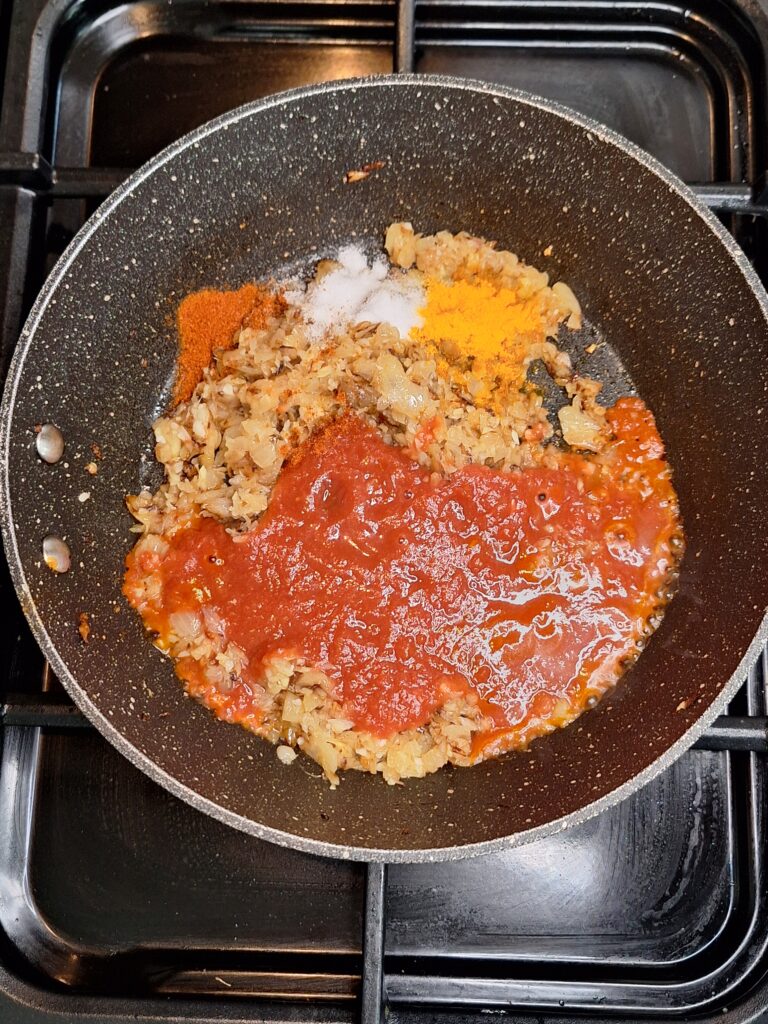 Tomato and spices added to browned onions
