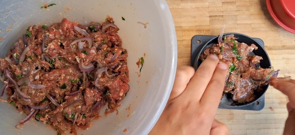 Making spicy beef burgers in burger press