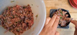 Making spicy beef burgers in burger press